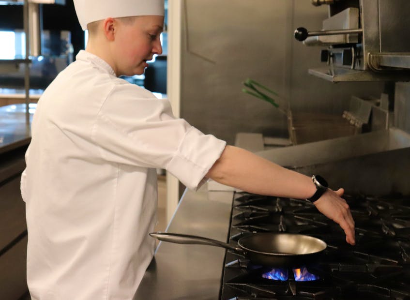 Jillian Clark, a former chemist attending the Culinary Institute of Canada, demonstrates how heat from a gas range spreads outwards and warms the area around the pan. - Logan MacLean